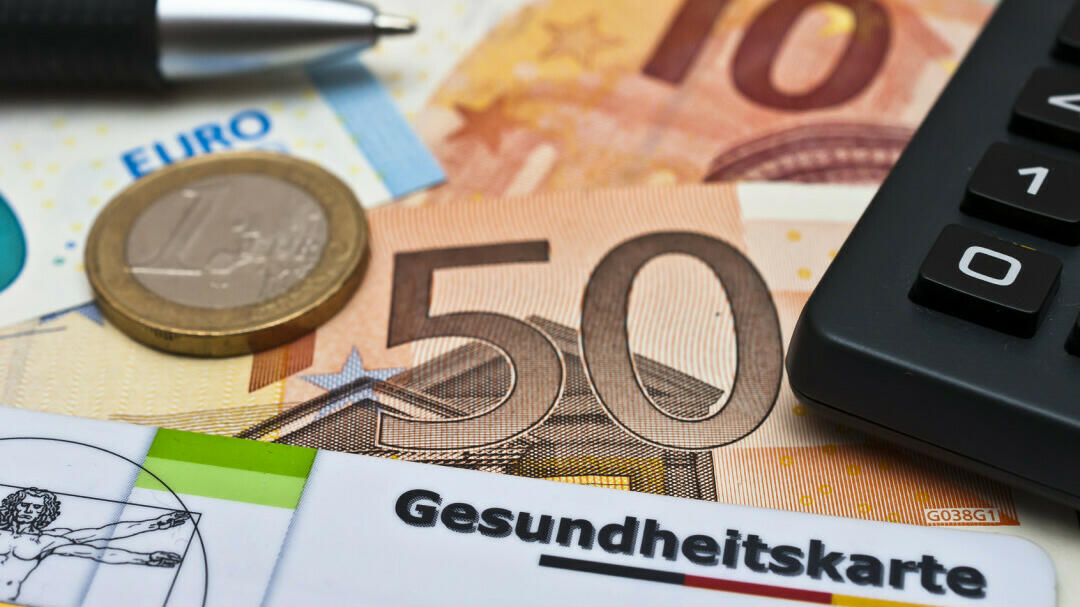 2 Geldscheine, eine Münze und eine Gesundheitskarte sind zu sehen