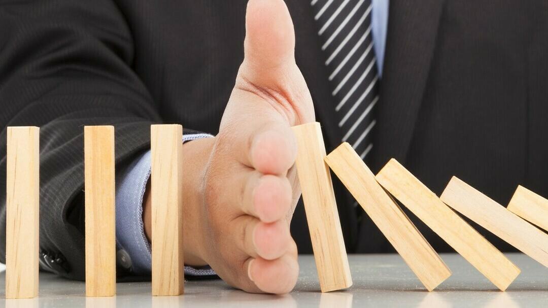 Hand wirft Holzklötze wie beim Domino um