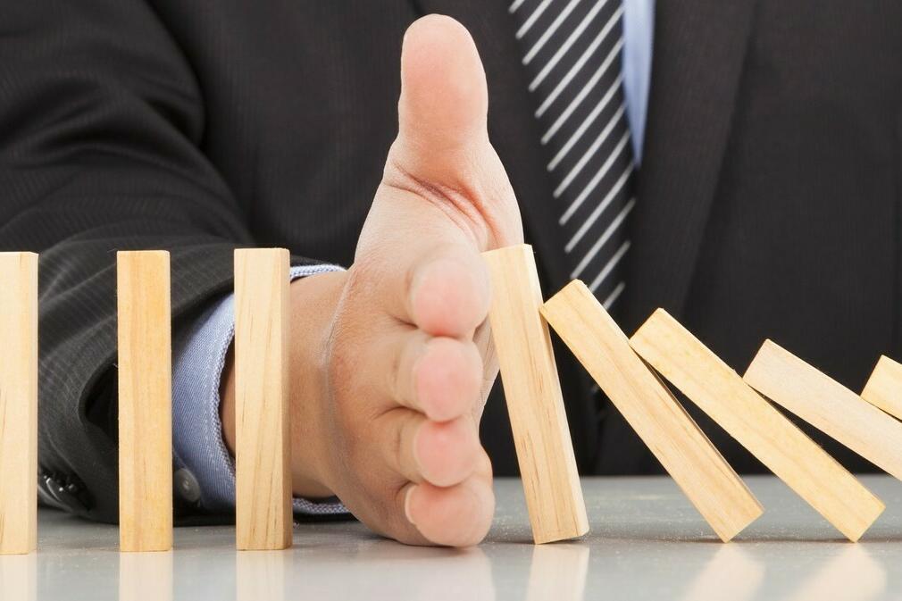 Hand wirft Holzklötze wie beim Domino um