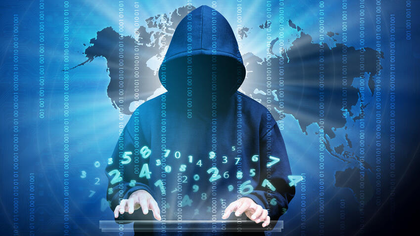 Düster aussehender Mensch vor Weltkarte tippt auf einem Laptop und Zahlen schwirren durch die Luft.